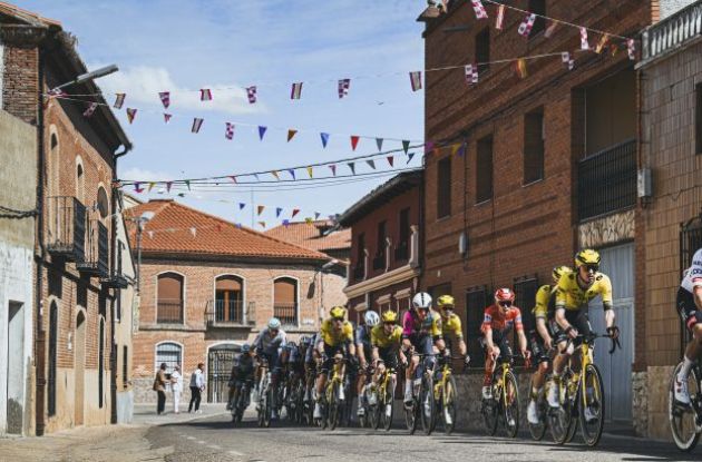 | Unipublic Cyclists passing through old village during stage 19 of Vuelta a Espana