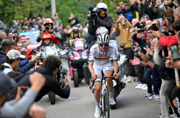 Tadej Pogacar climbing on his bike next to spectators