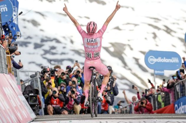 Tadej Pogacar raises arms as winner of stage 15 in snowy Livigno