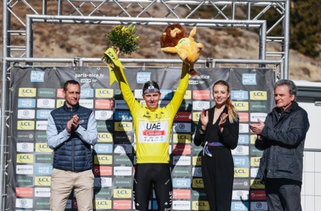 Tadej Pogacar celebrates his race lead on the podium wearing the yellow jersey