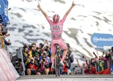 Tadej Pogacar raises arms as winner of stage 15 in snowy Livigno